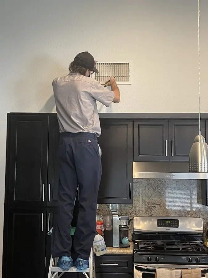Technician inspecting an air vent during HVAC service in Munster